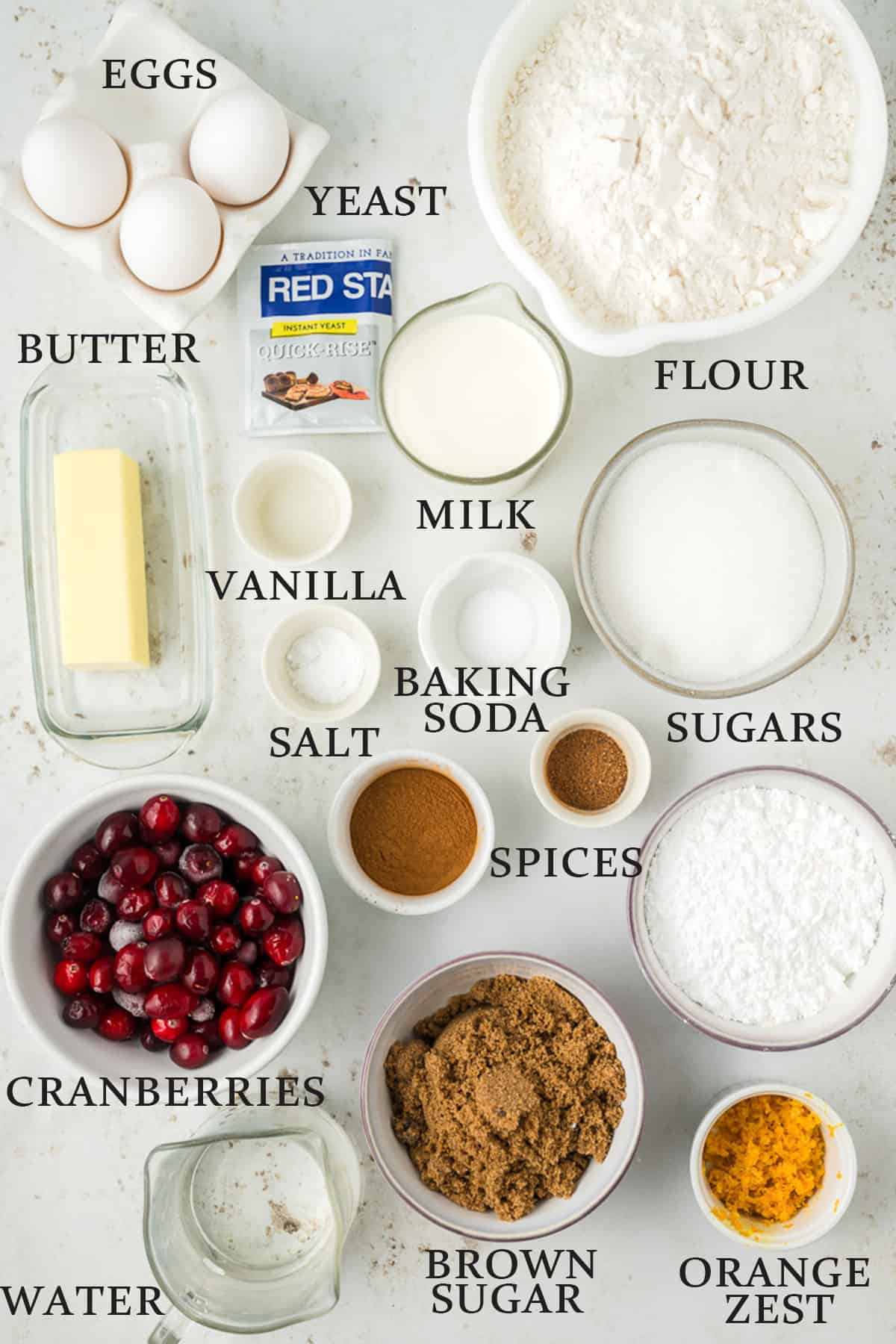Ingredients needed to make cranberry orange cinnamon rolls on a white background with text overlay,