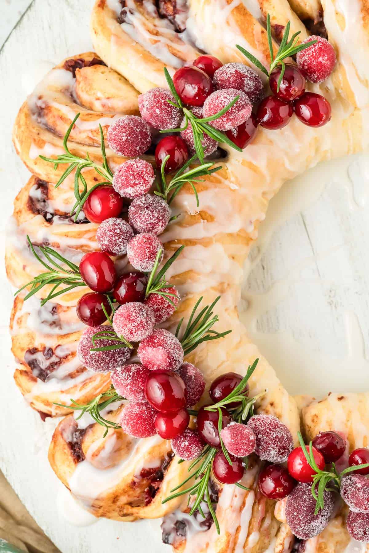 Close up of the sugared cranberries and rosemary decor on a cinnamon roll wreath.