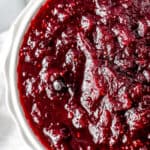 Close up of cranberry sauce in a white bowl with text overlay.