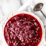 Cranberry sauce in a white bowl with a silver spoon and text overlay.