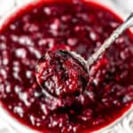 Cranberry sauce on a spoon over a bowl of more cranberry sauce.