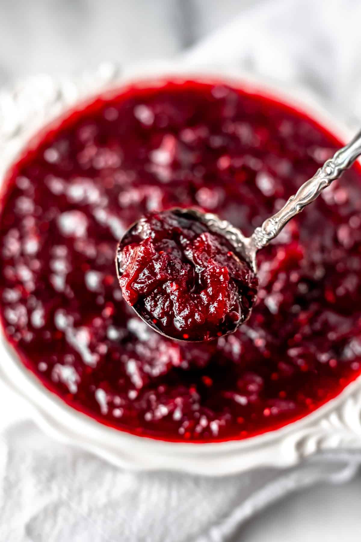 Cranberry sauce on a spoon over a bowl of more cranberry sauce.