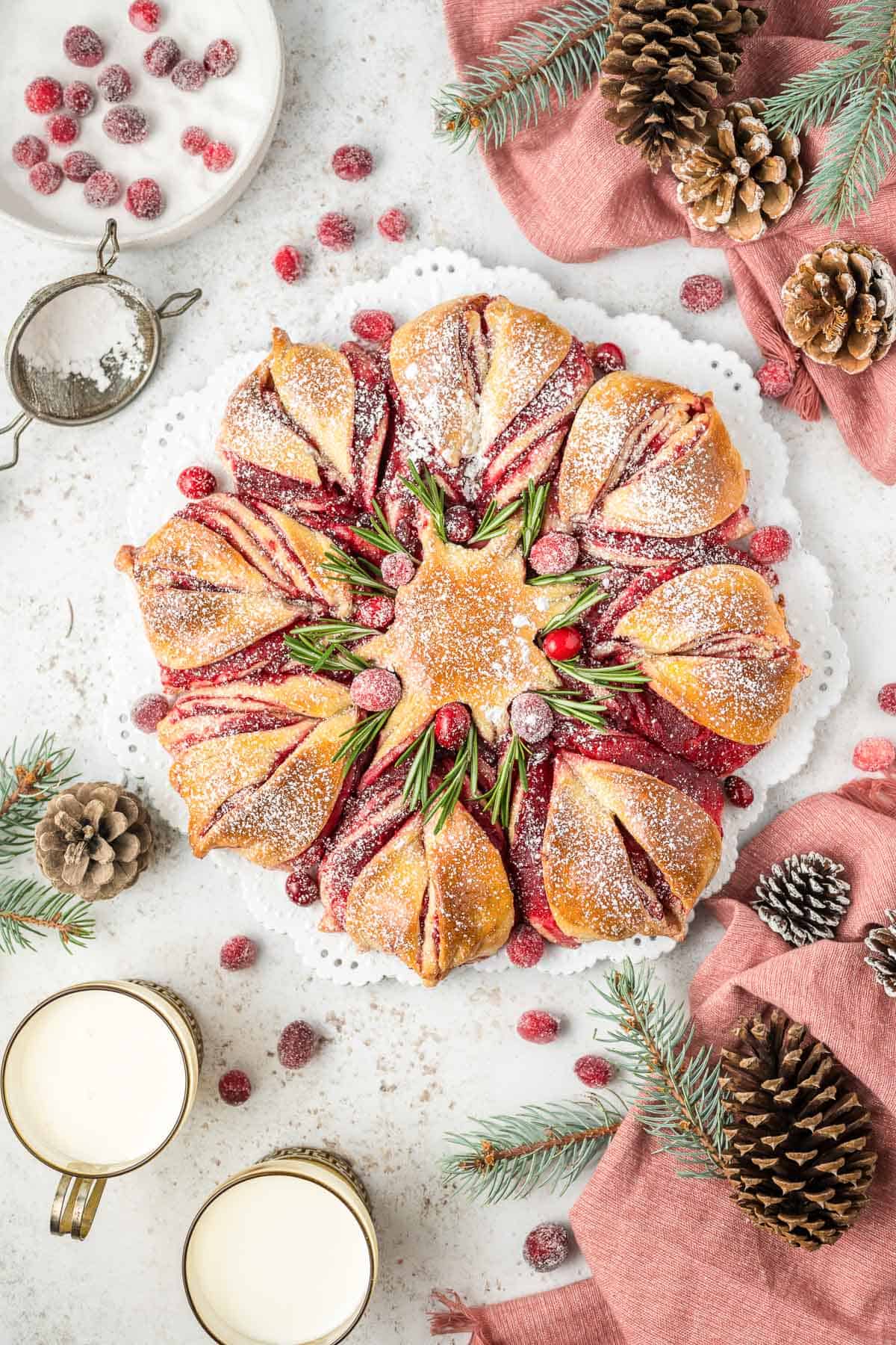 Overhead of a loaf of cranberry star bread with decor and ingredients around it.