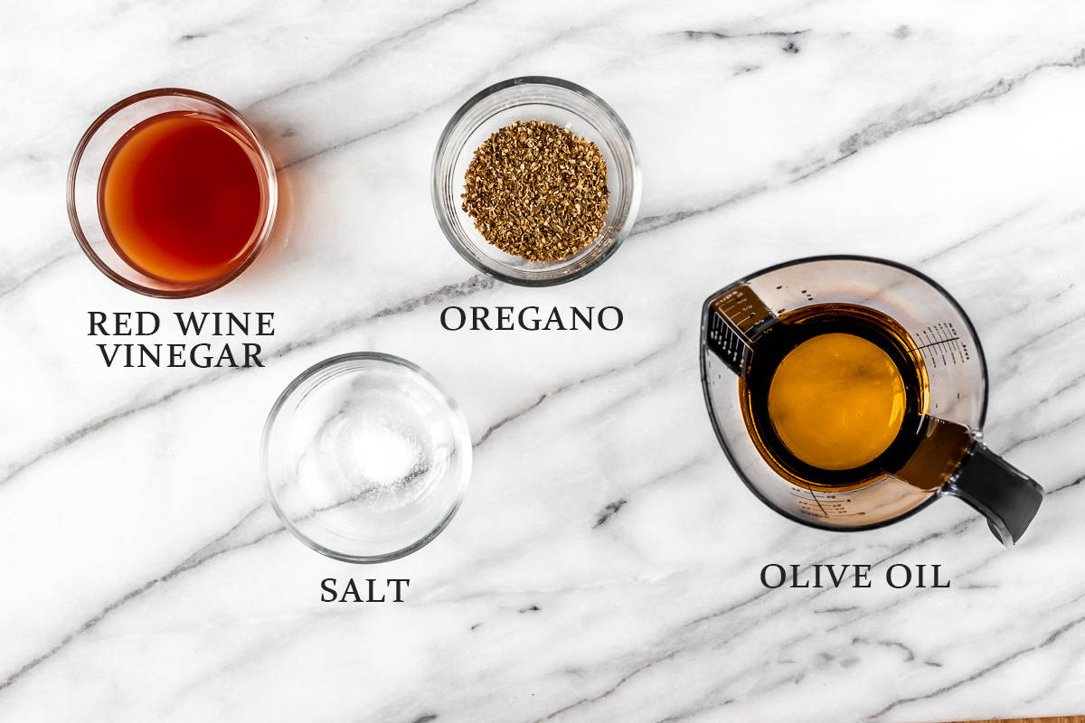 Ingredients to make Greek salad dressing on a marble background with text overlay.