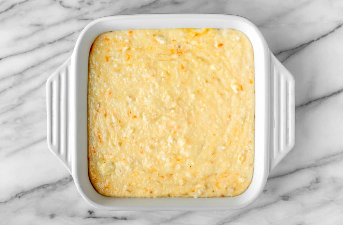 Cheesy grits and eggs in a white, square casserole dish.