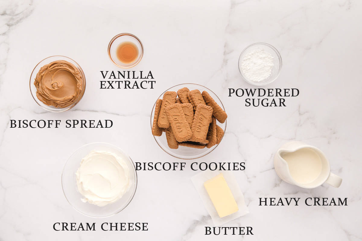 Ingredients needed to make mini Biscoff cheesecakes on a white surface with text overlay.