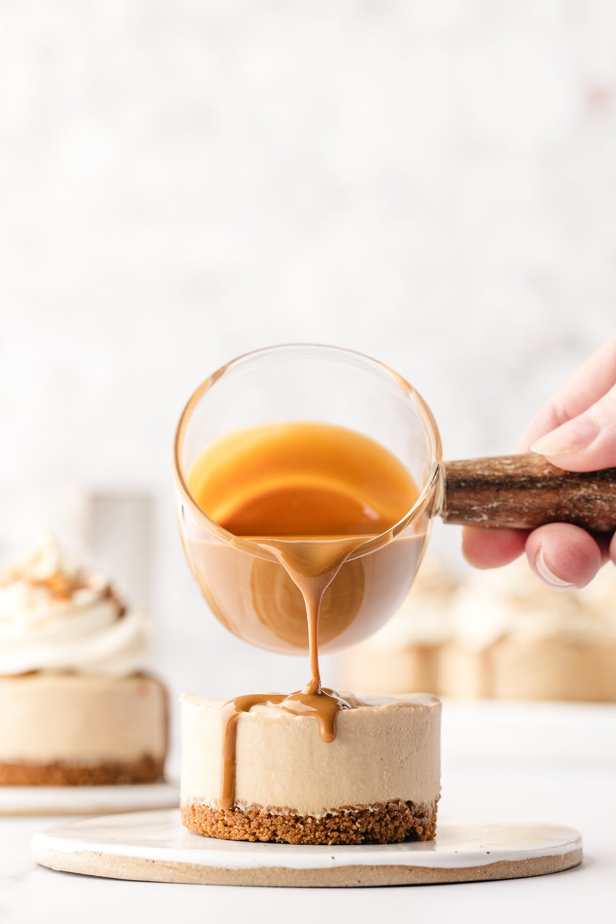 Warmed Biscoff spread being poured over a mini Biscoff cheesecake.