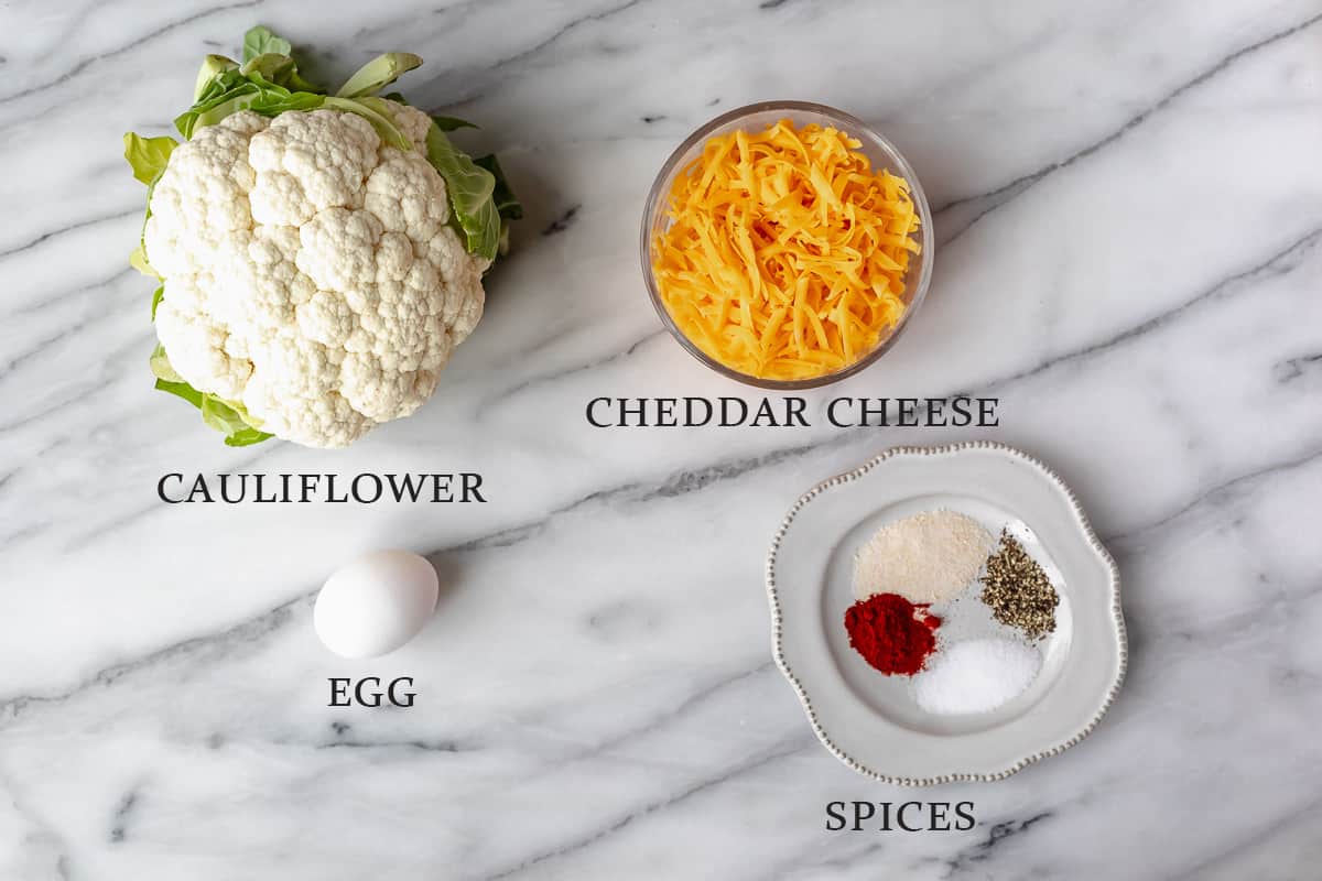 Ingredients needed to make cauliflower hash browns on a marble background with text overlay.