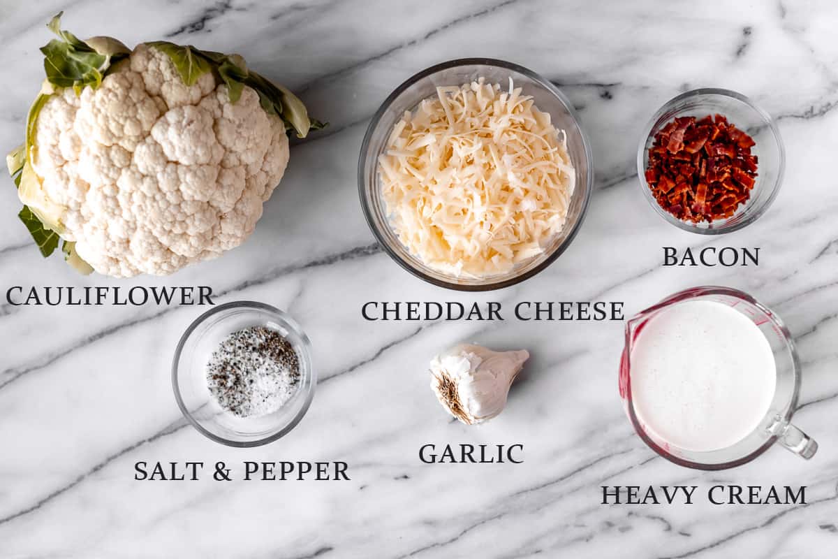 Ingredients needed to make keto au gratin cauliflower on a marble background with text overlay.