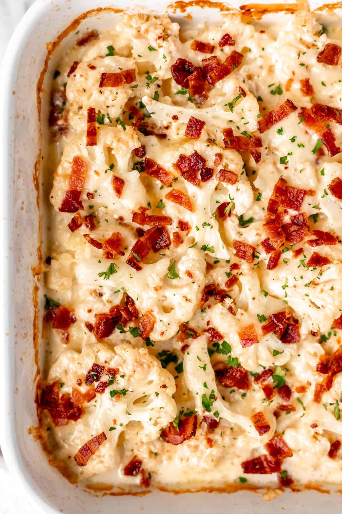 Close up overhead view of half of a casserole dish of keto au gratin cauliflower with bacon on top.