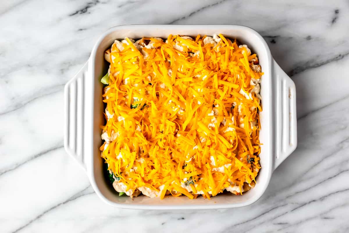 Cheese topped casserole in a white casserole dish on a marble background.