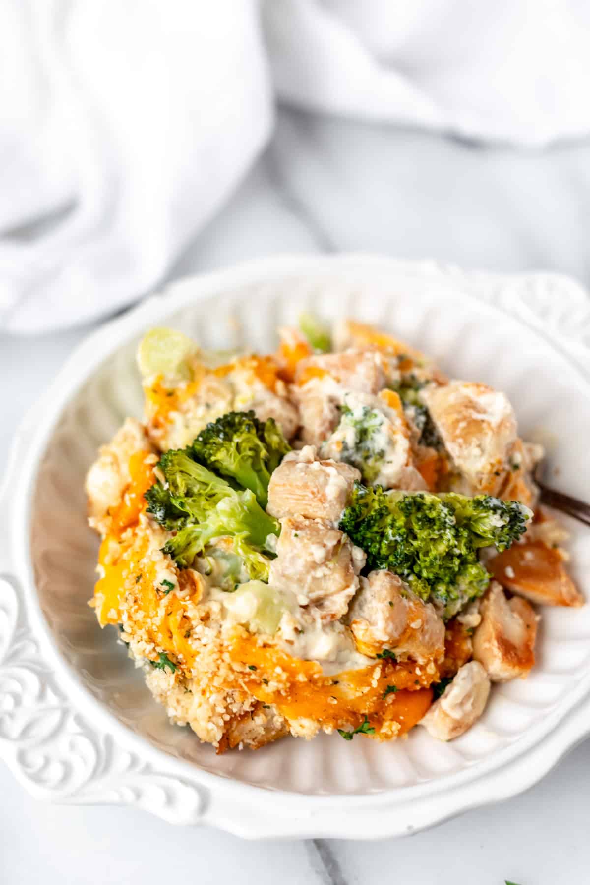 A white bowl full of keto chicken divan with a white towel in the background.