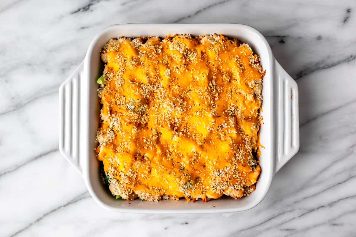 A baked keto chicken divan casserole in a white, square casserole dish on a marble background.