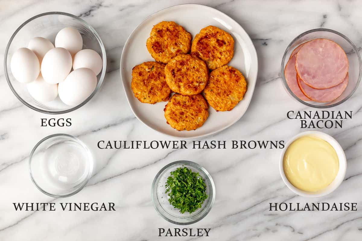 Ingredients needed to make keto eggs benedict on a marble background with text overlay.