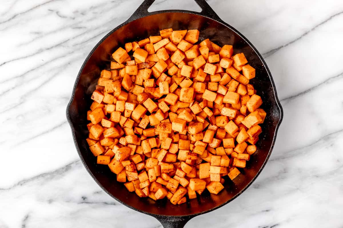 Diced sweet potatoes cooking in a skillet.