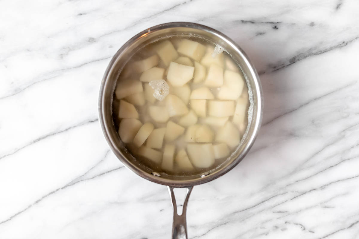 Boiled potatoes in a silver pot of hot water.