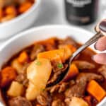 A spoonful of Guinness beef stew over a bowl of more stew with text overlay.