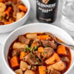 Two bowls of Guinness beef stew with a can of Guinness in the background and text overlay.