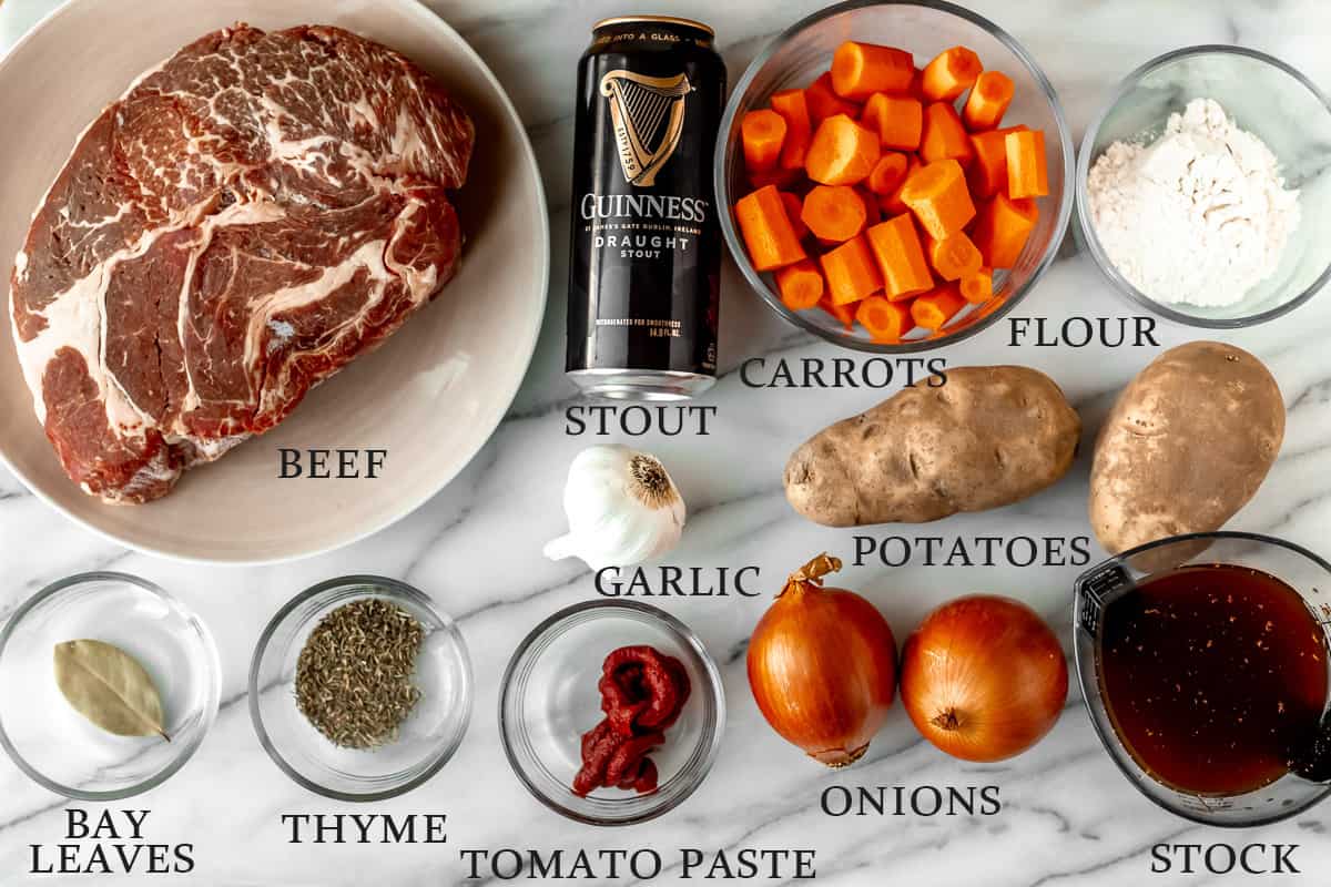 Ingredients needed to make Instant Pot Guinness Beef Stew on a marble background with text overlay.