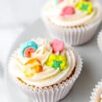 Lucky Charms cupcakes on a cake stand with extra marshmallows around them with text overlay.
