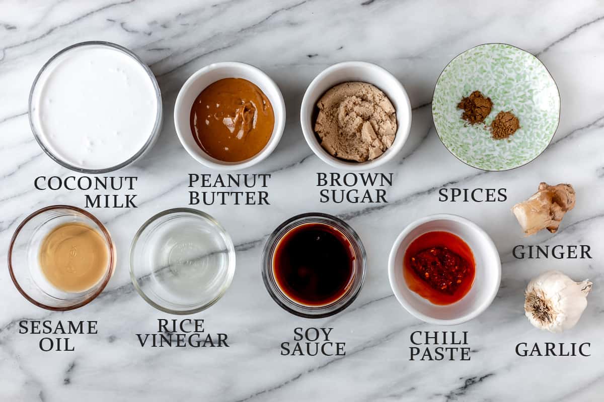 Ingredients needed to make peanut sauce on a marble background with text overlay.