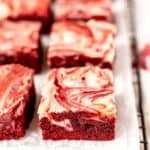 Red velvet cheesecake brownies on parchment paper with text overlay.