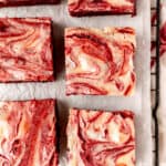 Red velvet cheesecake brownies on parchment paper with text overlay.
