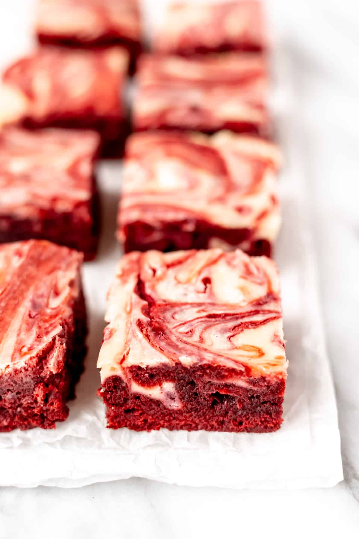 Red velvet cheesecake brownies on a sheet of parchment paper.