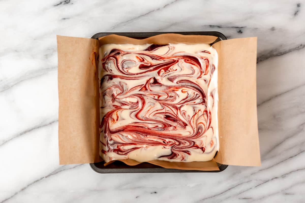 Cheesecake batter swirled into red velvet cheesecake batter in an 8-inch square baking pan.