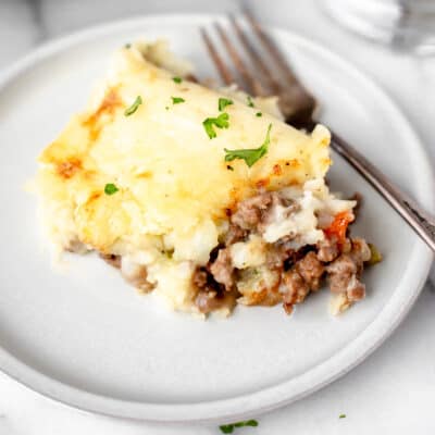 A serving of Shepherd's Pie on a white plate with a fork.