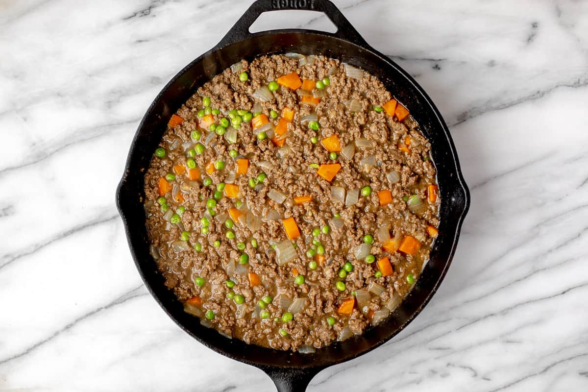 Shepherd's Pie filling of meat, carrots, and onions with gravy in a cast iron skillet.