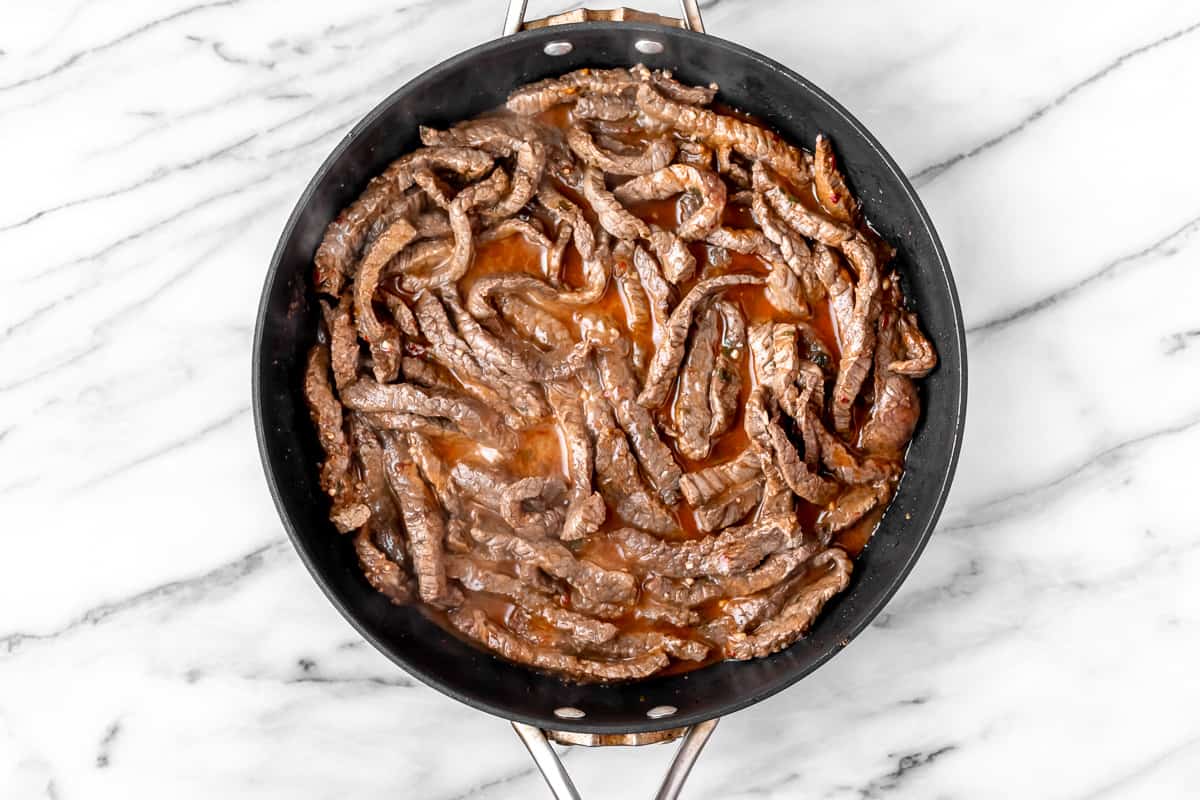 Cooked beef strips in a black skillet.