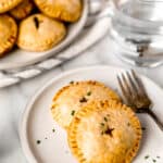 Two whole beef hand pies on a small white plate with a fork and text overlay.