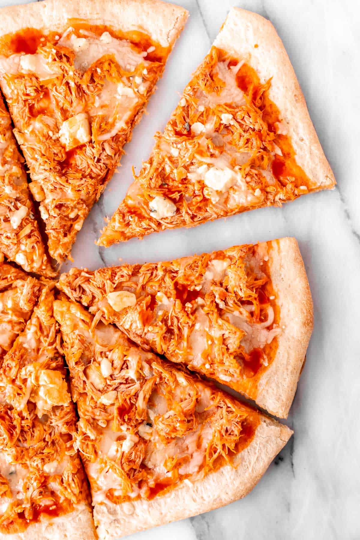 Overhead view of a buffalo chicken pizza cut into 8 slices on a white background.