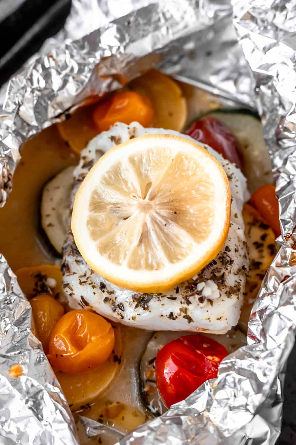 Baked cod in foil with vegetables and topped with lemon.