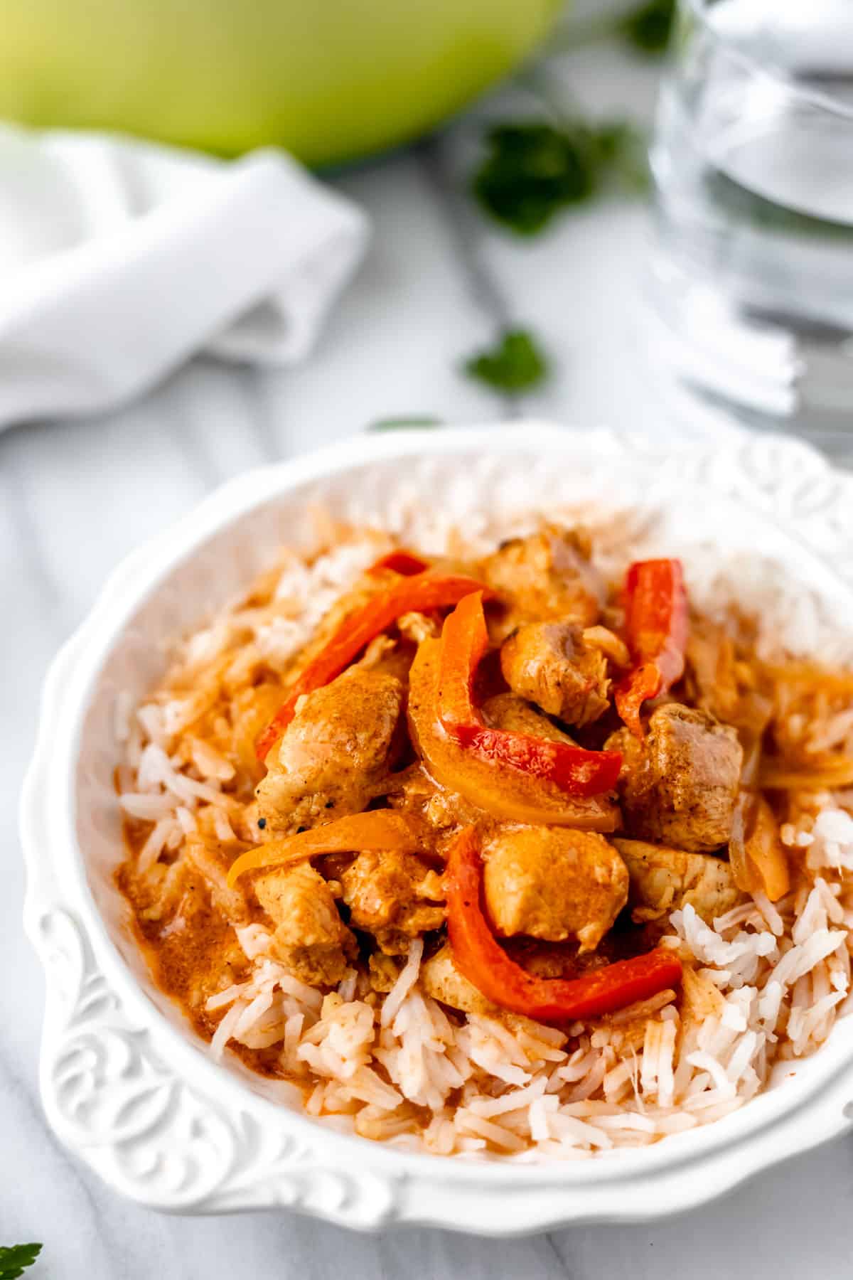 A white bowl of coconut curry chicken and rice.