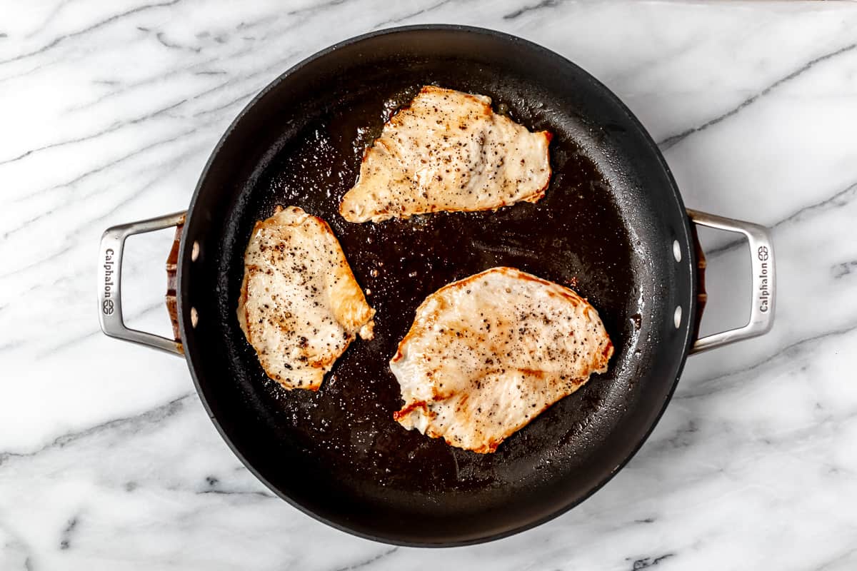 Three pieces of cooked chicken in a black skillet.