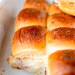 Ham and cheese sliders in a white casserole dish with text overlay.