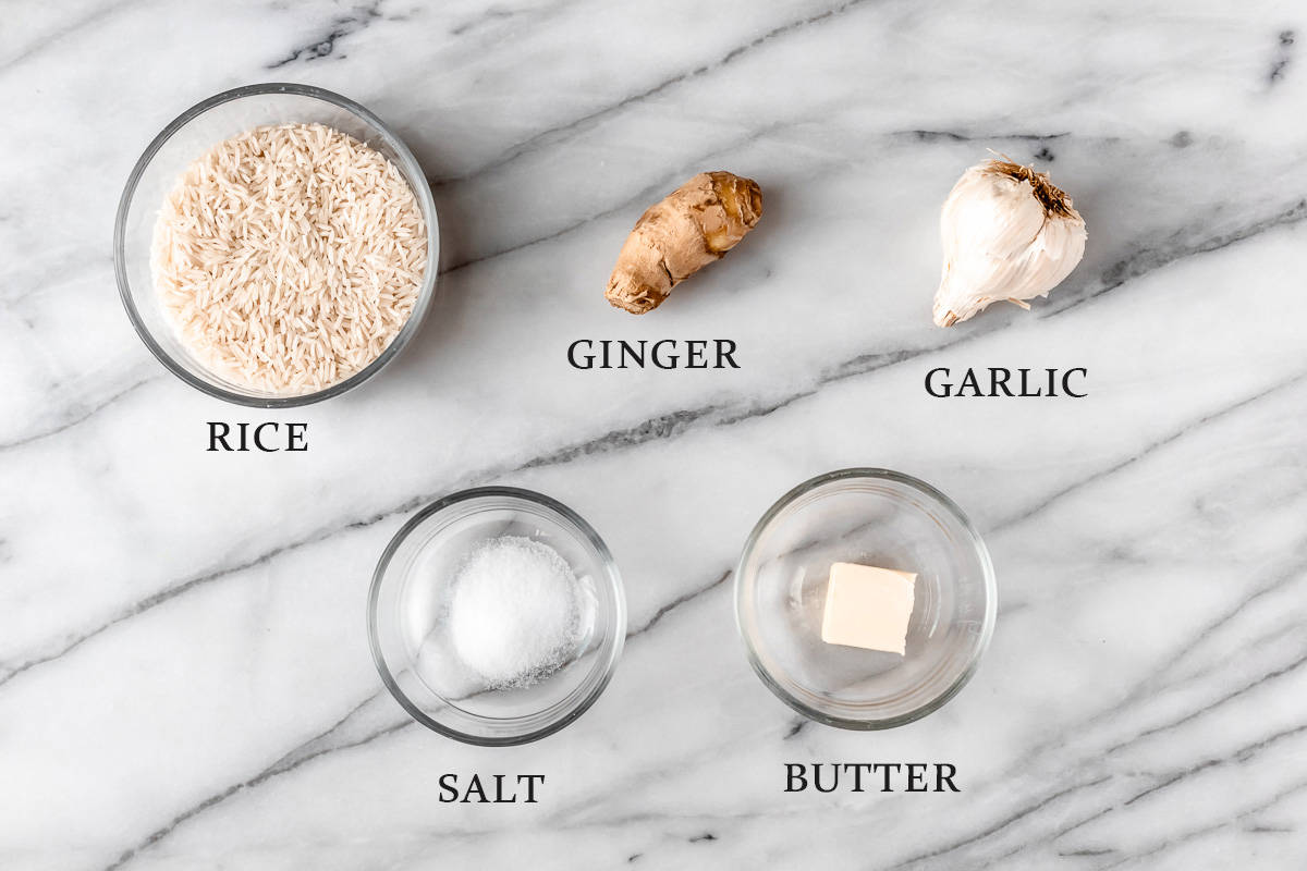 Ingredients needed to make ginger rice on a marble background with text overlay,