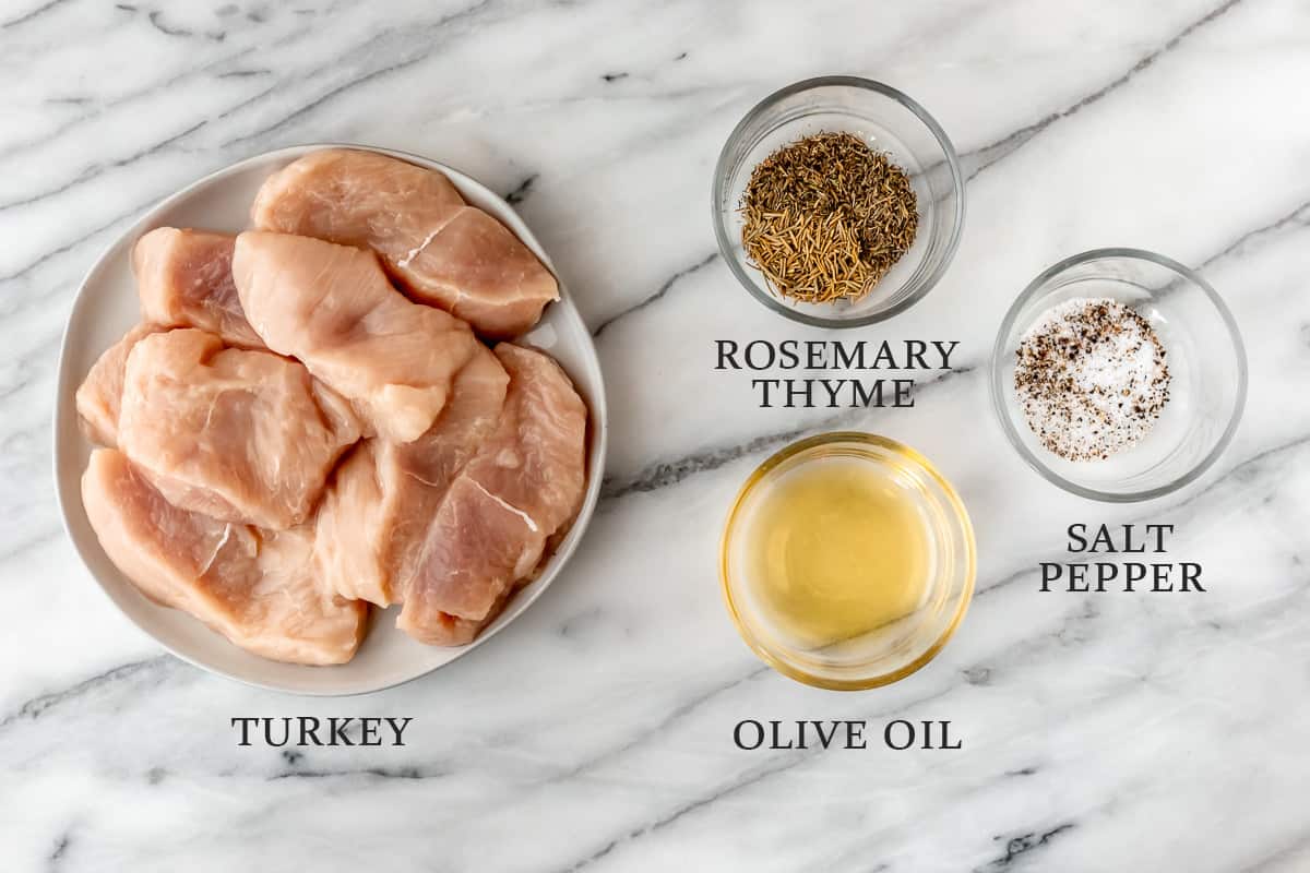 Ingredients needed to make turkey chops with rosemary and thyme on a marble background with text overlay.