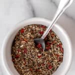 Tuscan seasoning in a small white bowl with a spoon in it with text overlay.