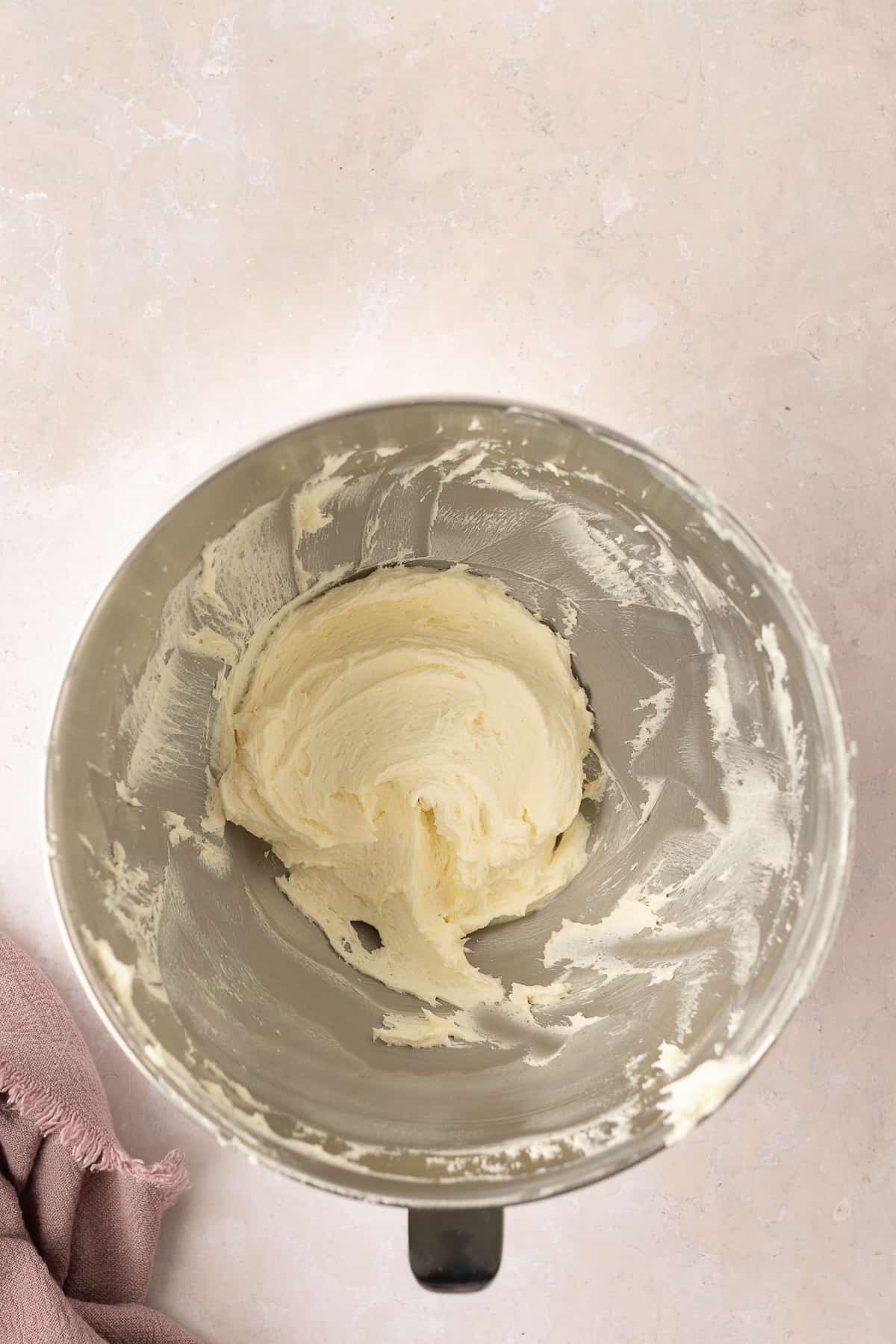 Whipped white chocolate ganache in a silver mixing bowl.