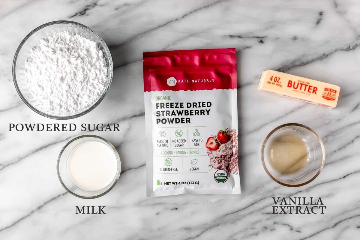 Ingredients needed to. make strawberry buttercream frosting on a marble background with text overlay.