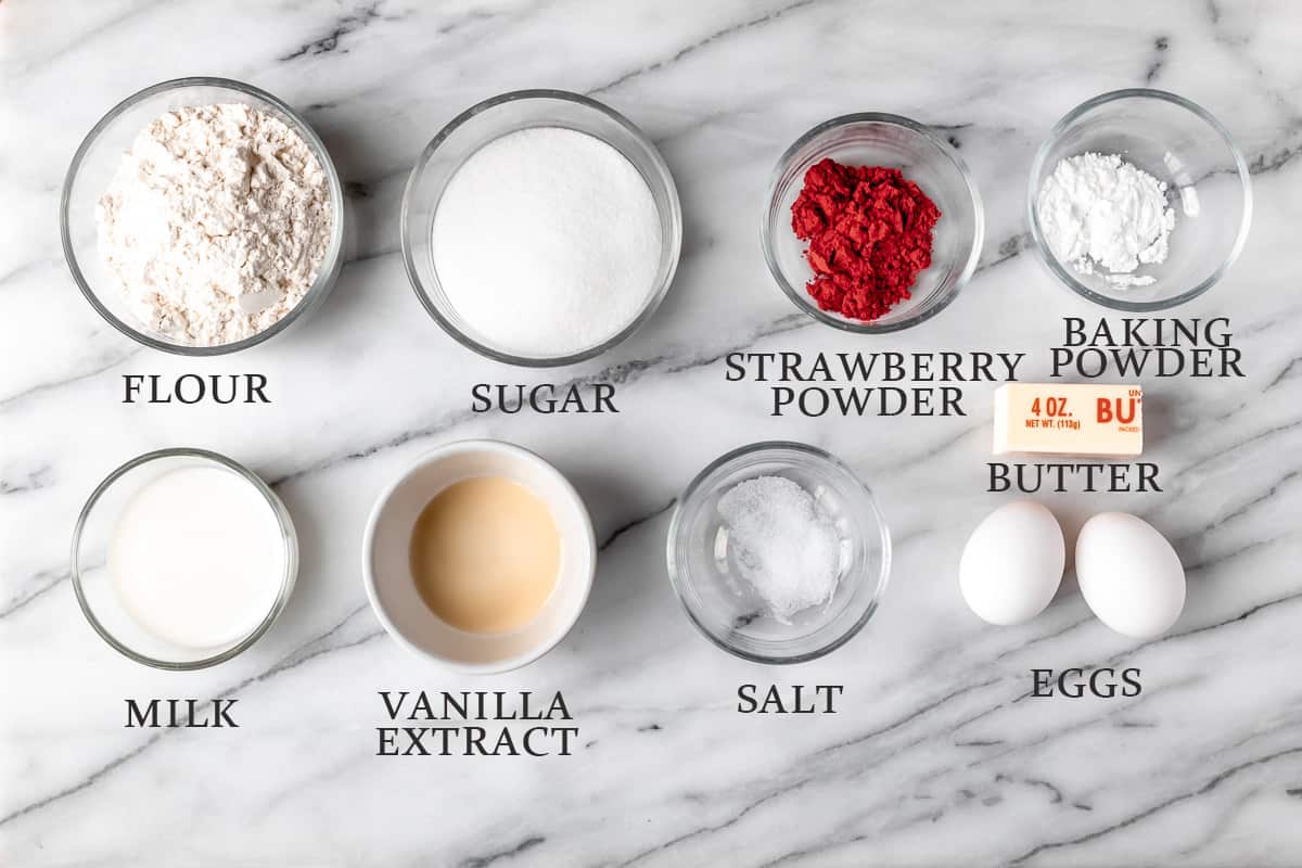Ingredients needed to make strawberry cupcakes on a marble background with text overlay.