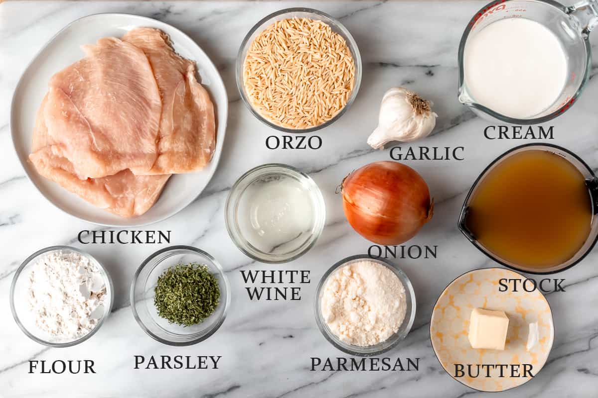 Ingredients needed to make parmesan chicken orzo on a marble background with text overlay.