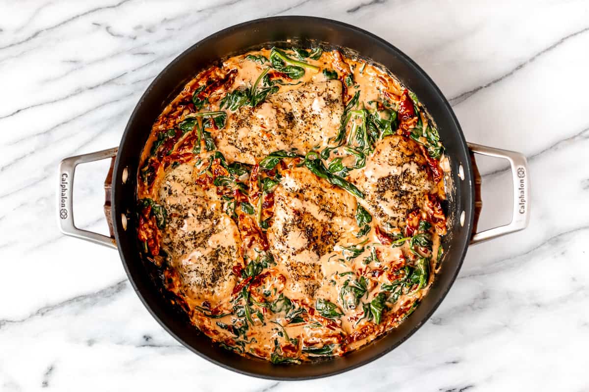 Creamy Tuscan Chicken with sun-dried tomatoes and spinach in a black skillet.