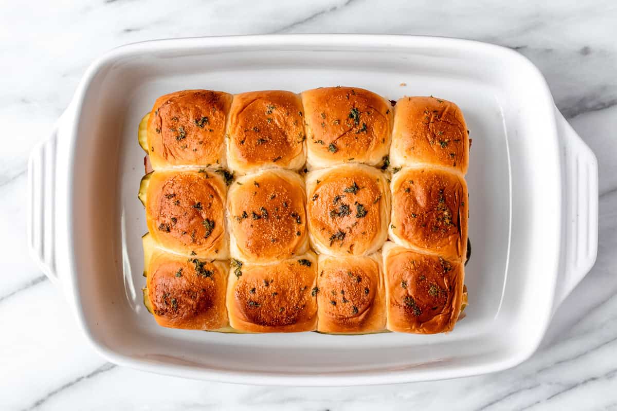 Overhead view of baked sliders in a white casserole dish.