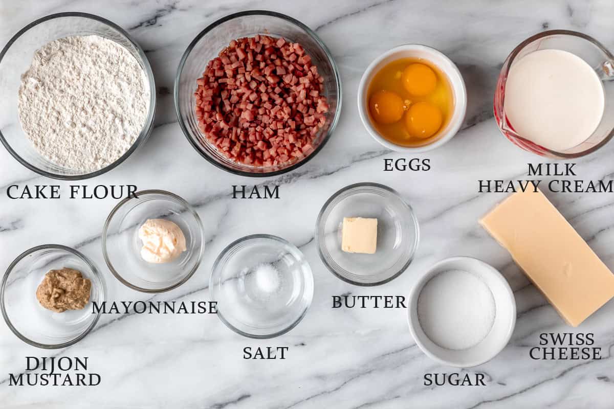 Ingredients needed to make ham and cheese crepes on a marble background with text overlay.