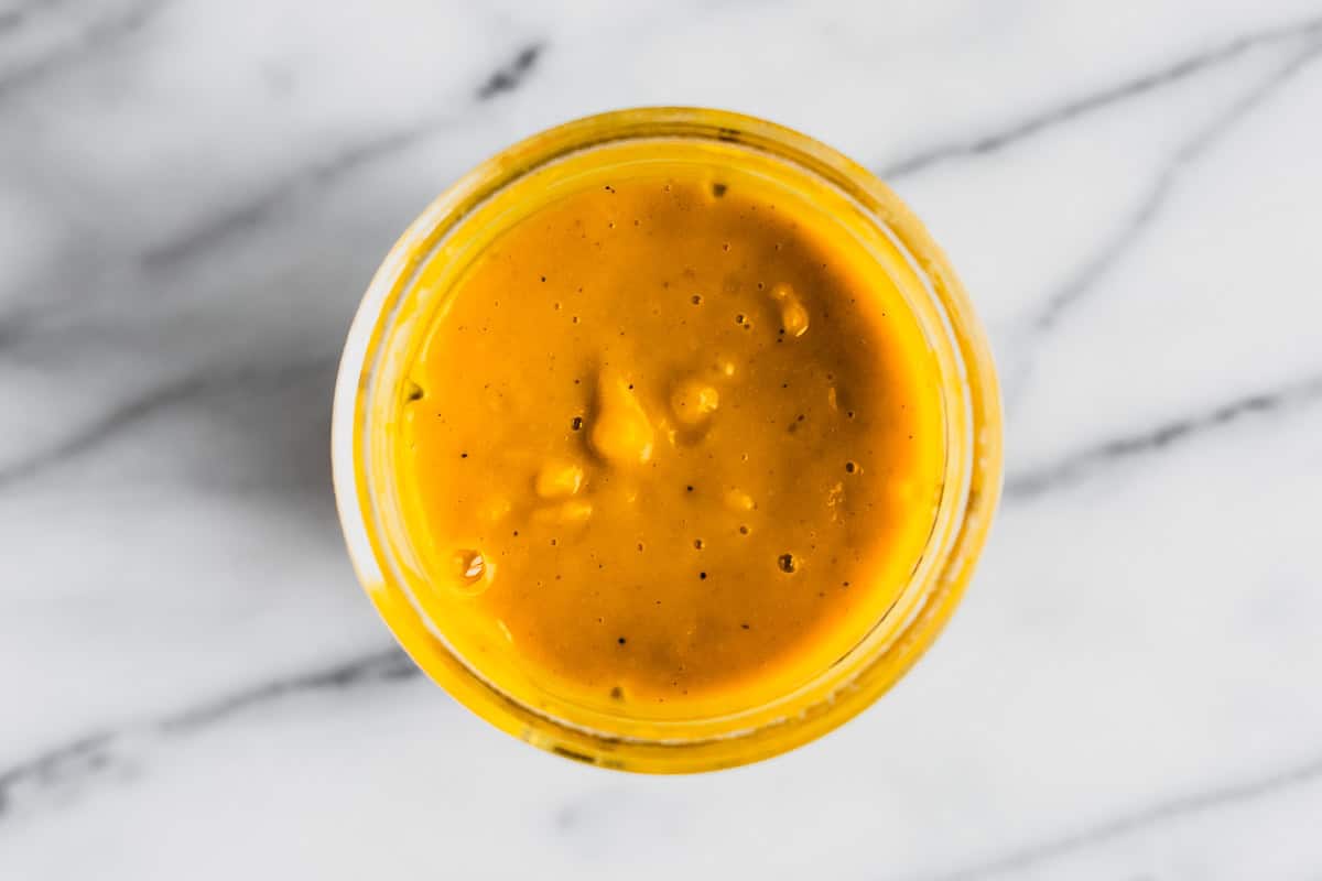 Butternut squash sauce in a blender cup over a marble background.