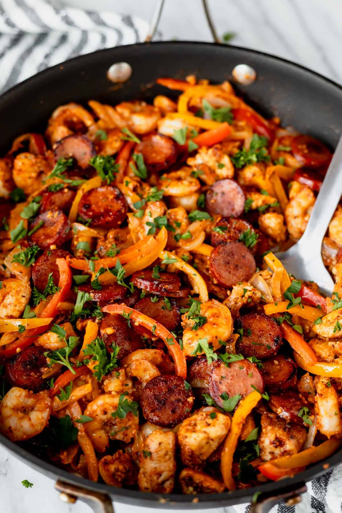 Close up of a black skillet filled with keto jambalaya with a spoon in it.